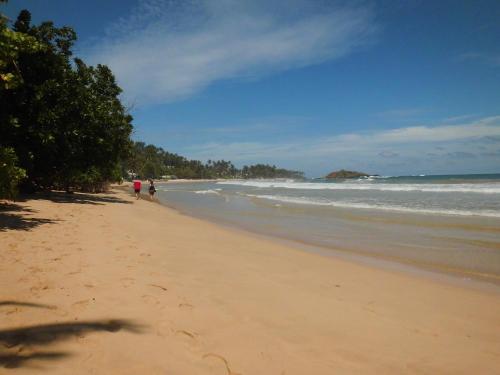 a beach with two people walking on the sand at Paradise Beach Club in Mirissa