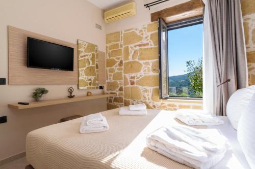 a bedroom with a bed and a tv and a window at Effrosini Panorama View in Nopíyia