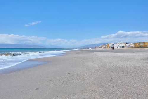 a beach with the ocean and a person walking on it at Apartamento Luna Cabo de Gata in El Cabo de Gata