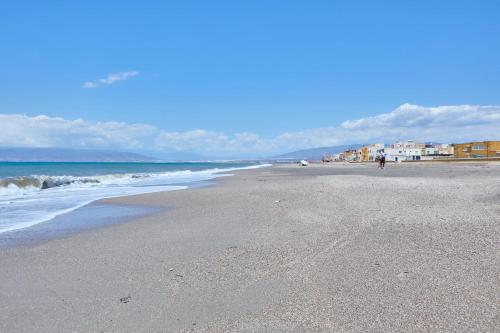 a beach with the ocean and a person walking on it at Apartamento Luna Cabo de Gata in El Cabo de Gata