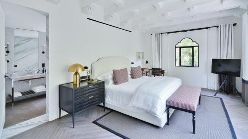 a white bedroom with a bed and a tv at Casa Polanco Hotel Boutique in Mexico City
