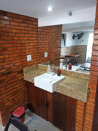 a kitchen with a sink and a brick wall at Pousada das Pedras in Itacuruçá