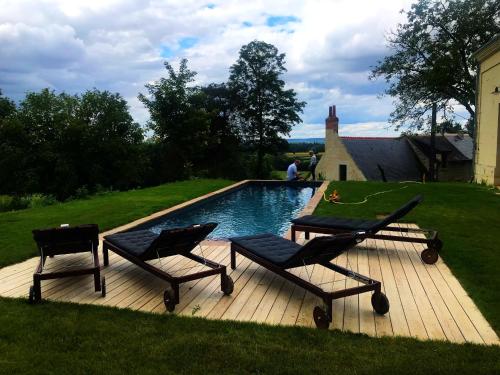 een zwembad met 2 stoelen en een tafel bij La Rigottiere in Huismes