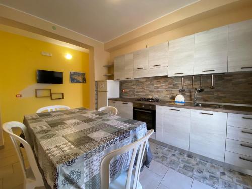 a kitchen with a table with chairs and a kitchen with a stove at 200m from the Sea - Large Private Patio with BBQ in Triscina