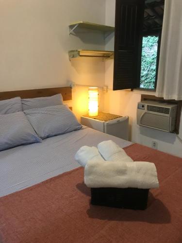 a bedroom with a bed with a lamp and a window at Céu Azul Pousada in Arraial d'Ajuda