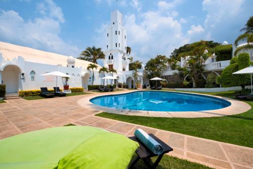 a pool in front of a white building with a church at Villa Bejar Cuernavaca in Cuernavaca