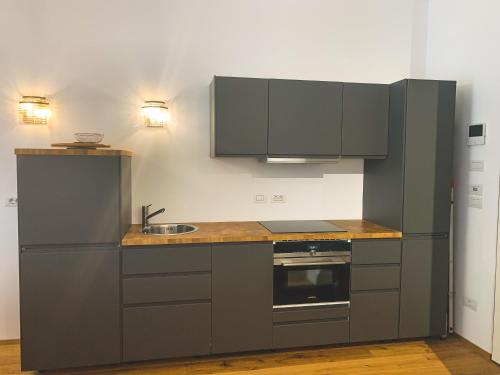a kitchen with gray cabinets and a sink at Palais Carducci in Bolzano