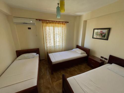 a room with two beds and a window at The First Hotel Saranda in Sarandë