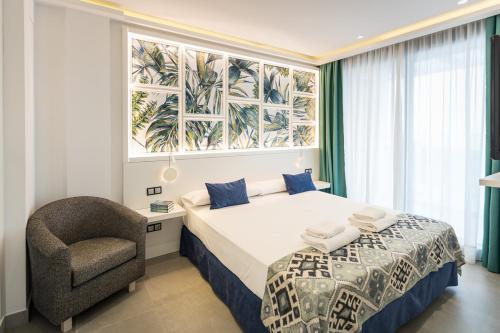 萨阿拉德洛斯阿图内斯Hotel Playa de la Plata的一间卧室，里面有一张床、一把椅子和一扇窗户