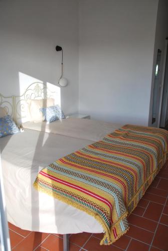 a white bed with a colorful blanket on it at Monte Ramos in Ferreira do Alentejo