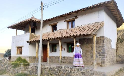 a woman standing in front of a house at Casa vivencial Mamá Vivi in Coporaque