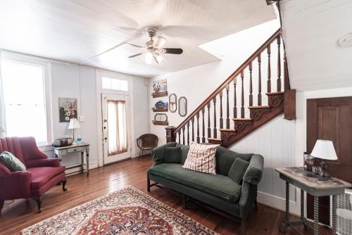 a living room with a green couch and a staircase at Armory Quarters A in Harpers Ferry
