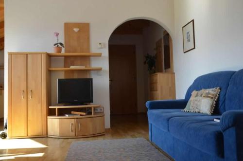 a living room with a blue couch and a tv at Bühel im Gschleier in Appiano sulla Strada del Vino