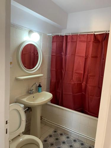 Łazienka z toaletą, umywalką i czerwoną zasłoną prysznicową w obiekcie Green Nondas Hill w Larnace