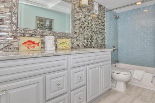 a bathroom with a sink and a toilet and a mirror at Anglers Cove 602 in St. Pete Beach