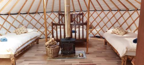 a room with two beds and a stove in a yurt at Shepherd's Loch Glamping in Turriff