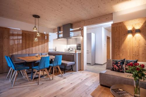 a kitchen and living room with a table and blue chairs at Griena NaturChalets **** in Mayrhofen