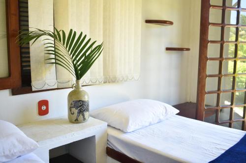 a vase sitting on a table next to a bed at Numa Boa HOSTEL Búzios in Búzios