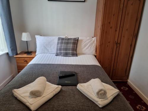 a bed with two towels and a laptop on it at The Cameo in Blackpool