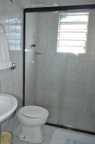 a bathroom with a shower and a toilet and a sink at Hotel Brasil Pindamonhangaba in Pindamonhangaba