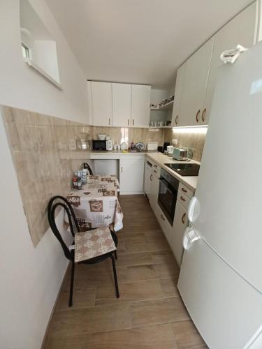 a small white kitchen with a table and a chair at Fazekas Vendégház in Balatonkeresztúr