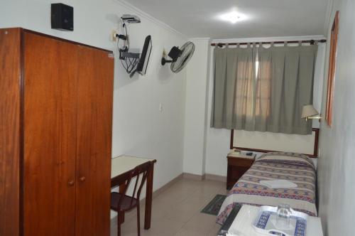 a small bedroom with a bed and a desk at Hotel Brasil Pindamonhangaba in Pindamonhangaba