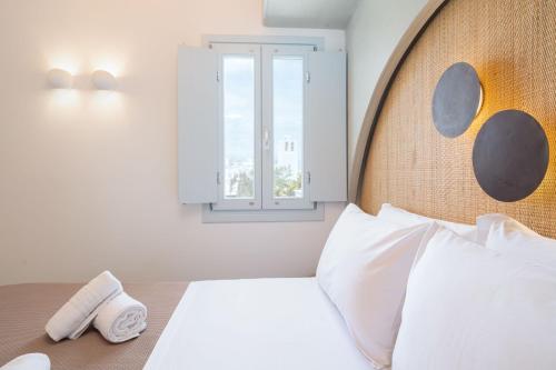 a bedroom with a bed with a wooden headboard and a window at Airth Santorini Suites in Firostefani