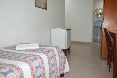 a bedroom with a bed and a small refrigerator at Hotel Brasil Pindamonhangaba in Pindamonhangaba