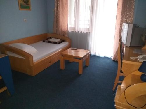 a small bedroom with a bed and a table at Garni Lupus prenoćište in Kanjiža