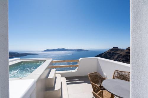 a balcony with a swimming pool and a table and chairs at Airth Santorini Suites in Firostefani