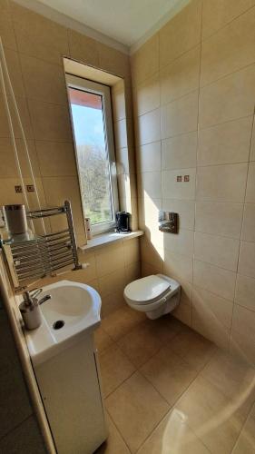 łazienka z umywalką, toaletą i oknem w obiekcie Bryza Międzyzdroje w mieście Międzyzdroje