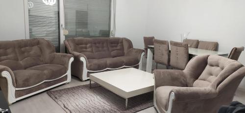 una sala de espera con sofás, mesa y sillas en Lovely 2 bedroom condo in Gjilan., en Gnjilane