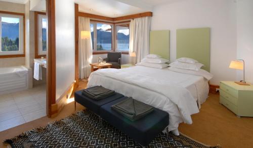 a bedroom with a large bed and a bathroom at Hostería Isla Victoria Lodge in Isla Victoria