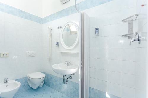 bagno con lavandino, servizi igienici e specchio di Hotel Lucerna a Cesenatico