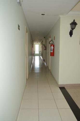 an empty hallway with white walls and white tile floors at Hotel Brasil Pindamonhangaba in Pindamonhangaba