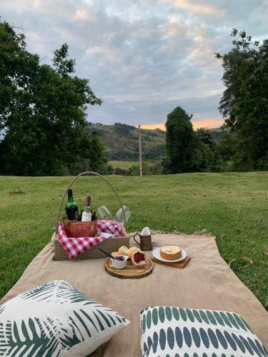 een picknick met eten en drinken op een kleed in een veld. bij Pousada Villa Tropea - Fazenda Chapadão in Serra Negra
