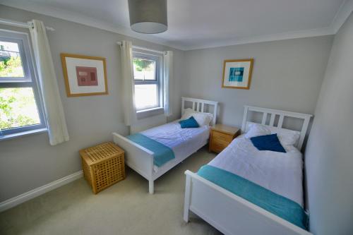 a bedroom with two beds and two windows at TorquayTownhouse with Hot Tub 200m from Beach - Free WiFi Sky Glass in Torquay