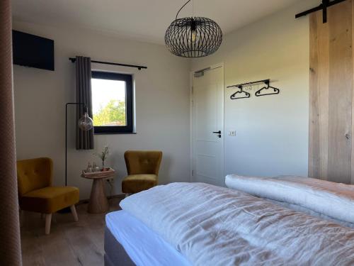 een slaapkamer met een bed, een stoel en een raam bij De Hoogstam in Vijlen