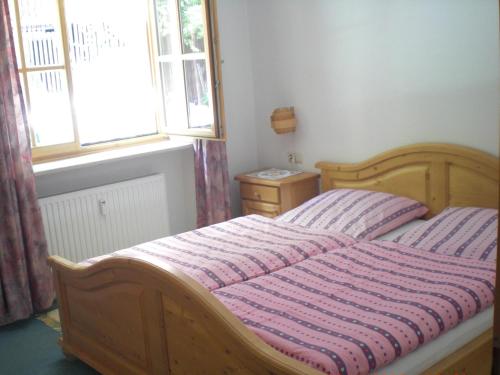 a wooden bed in a bedroom with a window at Ferienwohnung Ernst in Berchtesgaden