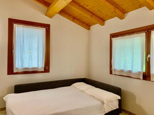 niewielka sypialnia z łóżkiem i 2 oknami w obiekcie Casa Al Piazzol w mieście Casera Campigolo