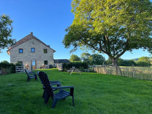 two benches sitting in the grass in front of a house at De Hoogstam in Vijlen