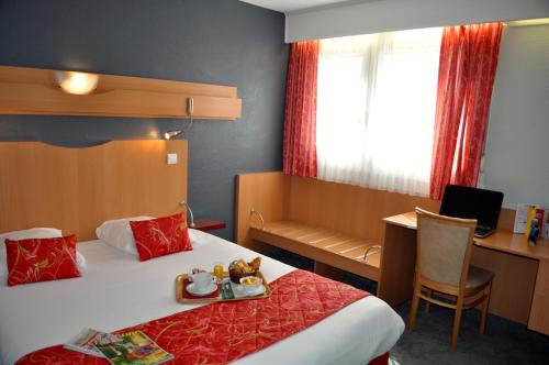 a hotel room with a bed and a desk with a computer at Atalante in Annemasse