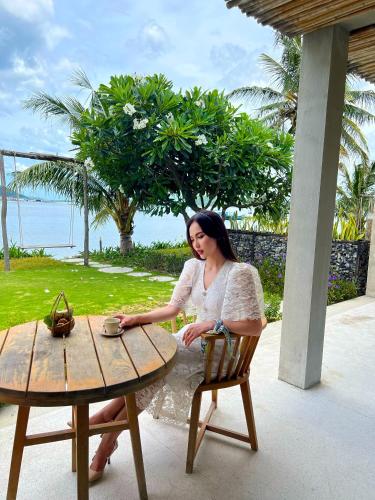a woman sitting at a table next to a table at Que Toi Village Resort Phu Yen in Song Cau