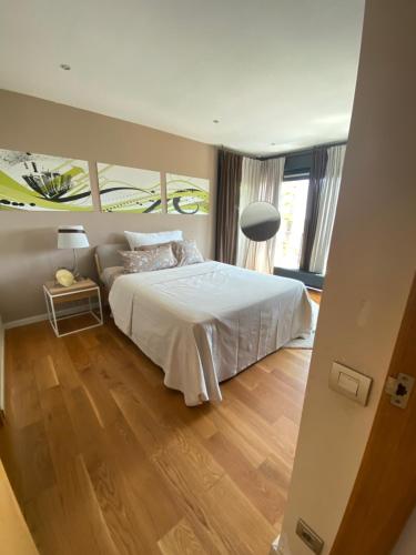 a bedroom with a white bed and a wooden floor at Ece Golden Villa Amazing 4 bedroom vila with pool in Alella