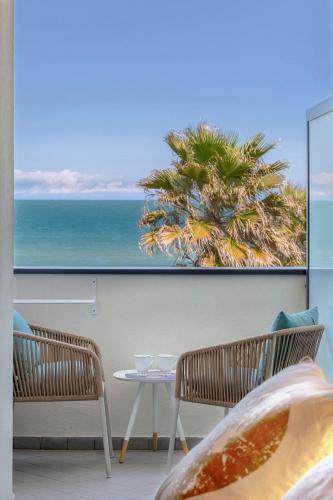 a room with two chairs and a table and a palm tree at Hotel Commodore in Riccione