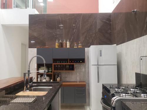 a kitchen with a sink and a white refrigerator at Casa do Barco Azul em Ubatumirim in Ubatuba