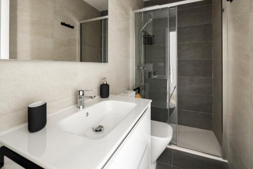 a white bathroom with a sink and a shower at La Casa de Lima Little Apartments in Cádiz