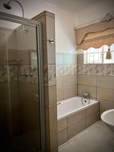 a bathroom with a shower and a tub and a sink at Lemon Rose Guest House in Virginia