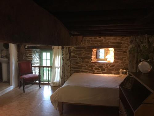 a bedroom with a bed and a stone wall at La Vigne, La Ville Josse in Plessala