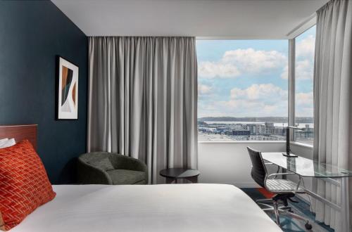 een hotelkamer met een bed, een bureau en een raam bij Rydges Auckland in Auckland